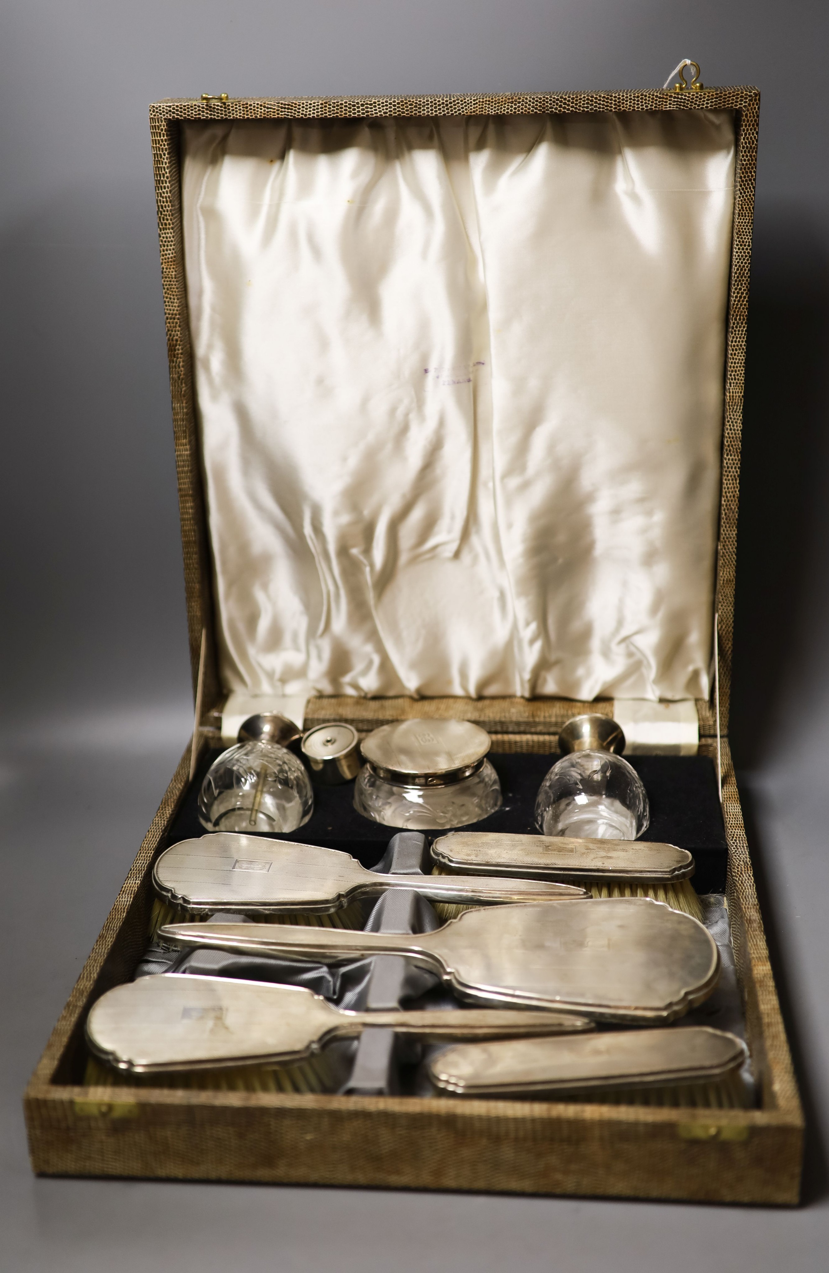 A late 1940's cased silver mounted eight piece dressing table set with atomiser, scent bottle and powder bowl.